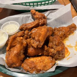 I got the O'Neil Buffalo sauce . - A basket of fried chicken wings with two dipping sauces, served on a paper-lined tray at a restaurant.