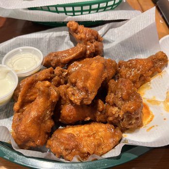 St James Irish Pub - I got the O'Neil Buffalo sauce . - A basket of fried chicken wings with two dipping sauces, served on a paper-lined tray at a restaurant. - Irish Near Me - Fall River, Massachusetts