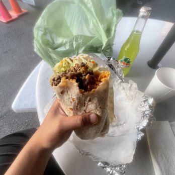 El Saborcito - a hand holding a burrito - Tacos Near Me - Seattle, Washington El Saborcito - a hand holding a burrito - Tacos Near Me - Seattle, Washington