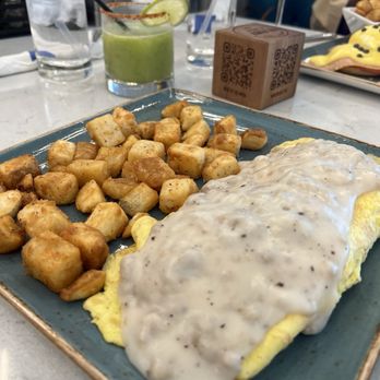 The Brunch District - Biscuit and gravy omelette with potatoes. - Breakfast & Brunch Near Me - Addison, Texas The Brunch District - Biscuit and gravy omelette with potatoes. - Breakfast & Brunch Near Me - Addison, Texas