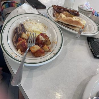 Russ's - Russ's House Special #3 - A breakfast meal with fried eggs, home fries topped with ketchup, bacon, and a sandwich on a diner table with condiments and a phone. - Diners Near Me - Springfield, Massachusetts