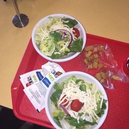 two bowls of salad on a red tray