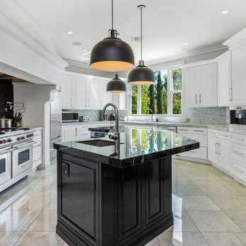 The Forest Group - a kitchen with white cabinets and a black island - General Contractors Near Me - Burbank, California