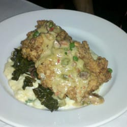 Shango New Orleans Bistro / Wine Bar - Buttermilk fried free range Chicken, cheddar cheese & green onion grits, bacon,  greens, Andouille sausage gravy.. 20