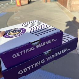 a person holding two boxes of cookies a person holding two boxes of cookies