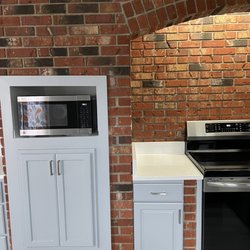 They custom built a cabinet for the microwave and pots and pans without removing a single brick!