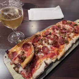 Sicilian-style pepperoni and sausage slice with crisp edges, melty cheese, and a cold beer on the side. Sicilian-style pepperoni and sausage slice with crisp edges, melty cheese, and a cold beer on the side.