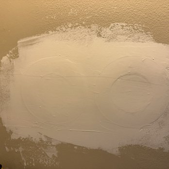 Terra Insulation - A beige wall with a large patch of white paint applied, featuring two circular markings and uneven edges. - Insulation Installation Near Me - Gaithersburg, Maryland