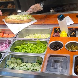 a person preparing a sandwich in a deli a person preparing a sandwich in a deli
