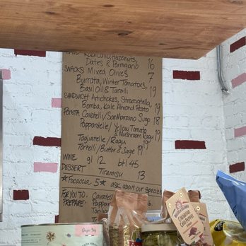 Tortelli - Tagliatelle Al Ragu - A handwritten menu on brown paper displays food and drink options, including pasta, wine, and desserts, in a store or cafe setting. - Italian Near Me - Brooklyn, New York