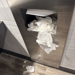 Most of the trash cans in the bathroom were full