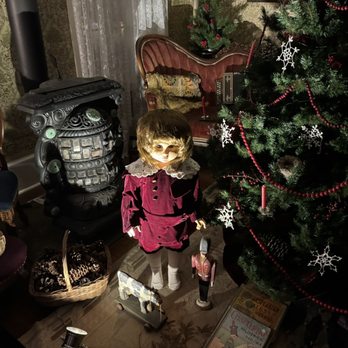 Door County Trolley - Ghost tour - A vintage doll dressed in a velvet outfit stands beside a decorated Christmas tree with snowflake ornaments and red beads. - Wine Tours Near Me - Egg Harbor, Wisconsin