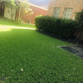 ATX Lawn Care - a green lawn in front of a brick house - Lawn Services Near Me