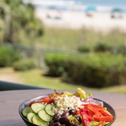 Reel - A salad on display at Reel Food & Drinks with a beach view in the distance