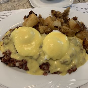 Kitchen 64 - Irish eggs Benedict - Eggs Benedict topped with hollandaise sauce, served with breakfast potatoes on a white plate at a diner. - Breakfast & Brunch Near Me - Middlebury, Connecticut