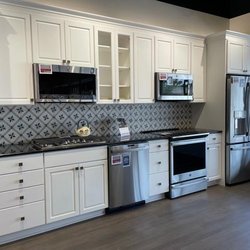 Bray & Scarff - Kitchen display with white cabinetry, stainless steel kitchen appliances, and blue tile backsplash