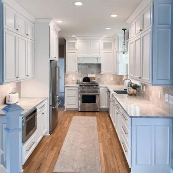 HK Pro Construction - a kitchen with white cabinets and a light wood floor - General Contractors Near Me