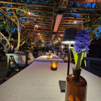 The Barn Kitchen - a table with a vase of flowers on it - American Near Me - Palm Springs, California The Barn Kitchen - a table with a vase of flowers on it - American Near Me - Palm Springs, California