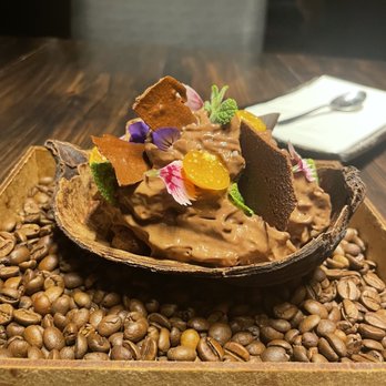 Nou Nikkei Cuisine - Chocolate mousse/ ice cream/ cake  served in a cacao pod on a bed of coffee beans and decorated with edible flowers and gooseberries. - Japanese Near Me - Curitiba, Puerto Rico