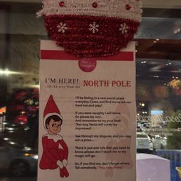 A Christmas ornament decorates a sign about Santa Claus at Rosa Mexicano in Hackensack, NJ, with a background of a window and city lights.