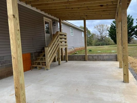 Covered concrete porch with custom porch - This porch area was done with a small retainer wall and poured concrete. Covered by roof added onto existing house roof and finished with custom steps per the customer request. Covered concrete porch with custom porch - This porch area was done with a small retainer wall and poured concrete. Covered by roof added onto existing house roof and finished with custom steps per the customer request.