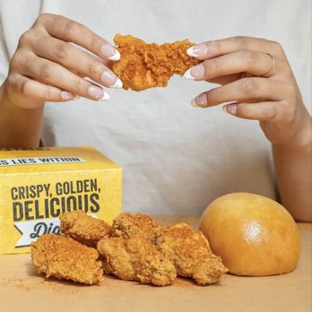 Golden Chick - a woman holding a piece of fried chicken - Fast Food Near Me - La Joya, Texas