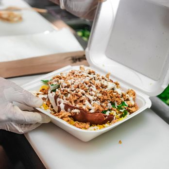 Fire Up Halal Grill - a person putting a container of food into a container - Halal Near Me - Tampa, Florida