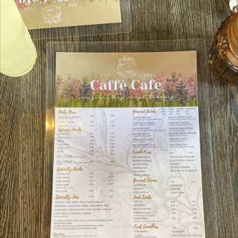Caffe Cafe - A printed menu from Caffé Cafe displaying various coffee, tea, and drink options on a dark wooden table. - Cafes Near Me - Brooklyn, New York