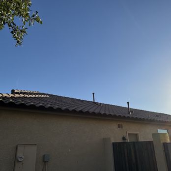 Monsoon Roofing - A residential building with a tiled roof is shown against a clear blue sky, with sunlight visible on the right side of the image. - Roofing Near Me - Gilbert, Arizona