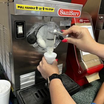 Taco Delite - a person pouring a drink into a machine - Mexican Near Me - Plano, Texas