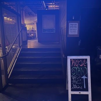 Char'd - A staircase with metal steps and handrails leads to an indoor dining area, with a chalkboard sign indicating to stand up the stairs. - Korean Near Me - Milwaukee, Wisconsin