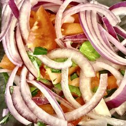 Side salad - way too many onions! - A detailed image of a fresh salad featuring sliced red onions, tomatoes, and leafy greens, likely served at a restaurant or cafe.