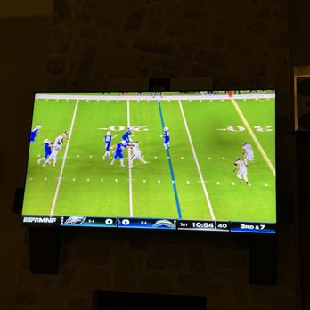 TexTech Systems - Excellent work - A TV shows an American football game with players in blue and white uniforms on a green field, with game details at the bottom. - Home Network Installation Near Me - Aubrey, Texas