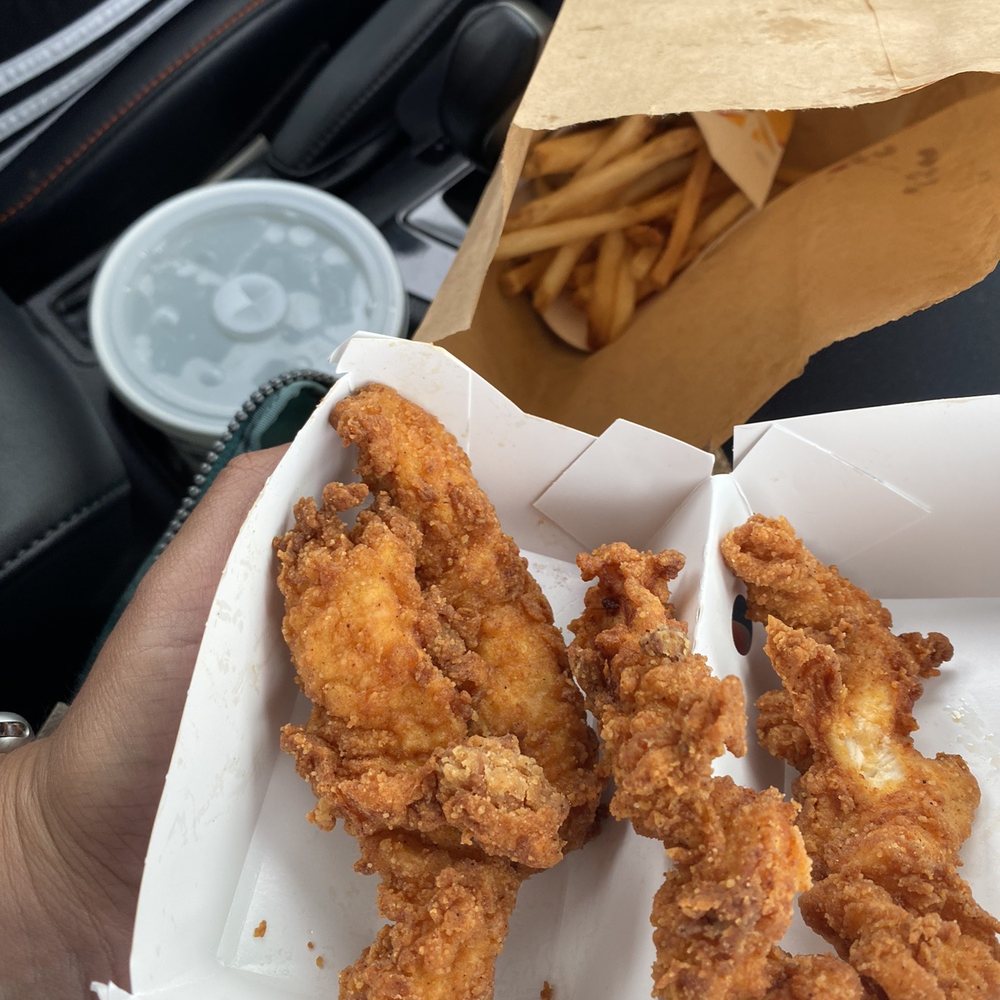 a hand holding a box of fried chicken a hand holding a box of fried chicken