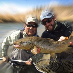 Trout Tales - Explore Utah with us. Guide Asher Koles with a big brown caught by his client, Darryl.