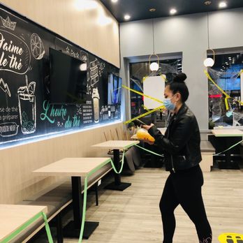 Presotea - a woman in a black jacket and black leggings holding a yellow rope in front of a chalkboard - Bubble Tea Near Me - Montreal, Quebec