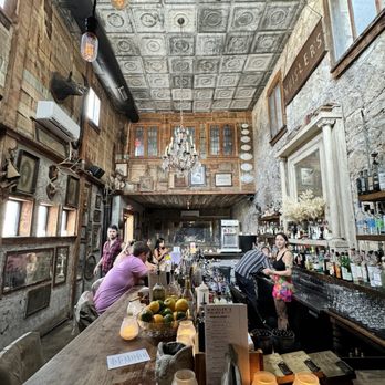 Whisler's - A bar interior at Whisler's features a high ceiling with decorative tiles, vintage decor, and patrons seated at the bar. - Cocktail Bars Near Me - Austin, Texas