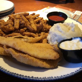 Red Lobster - Clam Strips Create Your Own Combination  Wild-Caught Whitefish (Golden-Fried) Mashed Potatoes - A plate features golden-fried whitefish fillets and clam strips, accompanied by a serving of mashed potatoes with gravy, and two small black containers of dipping sauces, one red and one white. The meal is served on a decorative white plate with a blue rim, placed on a wooden table at Red Lobster in Albuquerque, NM, as indicated by the caption. - Seafood Near Me - Albuquerque, New Mexico