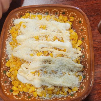 Cocina Azteca - Corn topped with mayonnaise, cheese, and sauce served on a decorative ceramic plate, likely at a Mexican restaurant. - Mexican Near Me - Ceres, California