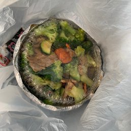 a tin foil container filled with broccoli, carrots, and beef a tin foil container filled with broccoli, carrots, and beef