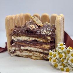 A rich, layered tiramisu with espresso-soaked ladyfingers, mascarpone cream, and silky hazelnut cream, topped with Ferrero Rocher