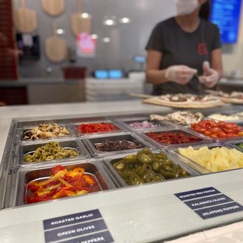 Pi Co - a woman preparing food in a buffet - Pizza Near Me - Toronto, Ontario