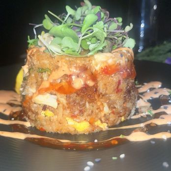Flavorture - Crab fried rice - Crab fried rice served in a round shape, garnished with microgreens and drizzled with sauces, presented on a black plate. - Bars Near Me - Washington, DC, District of Columbia