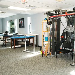 MOTION Sports Medicine - New City - Spacious rehab gym at MOTION New City featuring therapy tables, multi-functional strength training machine, and open floor layout for person