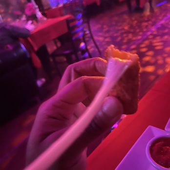 Cave Restaurant - a hand holding a piece of pizza - Lounges Near Me - Brooklyn, New York