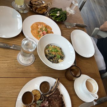Marmo - Bottom to top: Cowboy ribeye, squid ink pasta, lobster ravioli, broccolini, and rosemary potatoes. - Italian Near Me - Houston, Texas