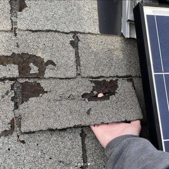Oakridge Resolutions - a person holding a solar panel on a roof - Solar Installation Near Me Oakridge Resolutions - a person holding a solar panel on a roof - Solar Installation Near Me