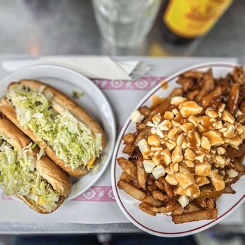 Paul Patates - two plates of food on a table - Poutineries Near Me - Montreal, Quebec Paul Patates - two plates of food on a table - Poutineries Near Me - Montreal, Quebec