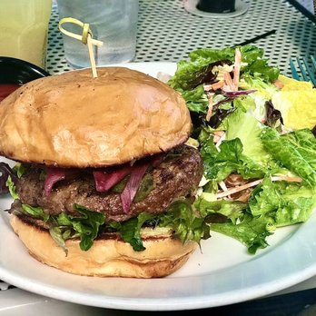 The Tipsy Trout - Elk Burger - A hamburger with a beef patty, lettuce, onions, and a bun, served with a side salad of mixed greens and vegetables. - American Near Me - Basalt, Colorado