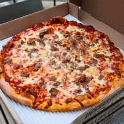Uccello's - Downtown - A round pizza with red sauce, melted cheese, and Italian sausage inside an open to-go pizza box...